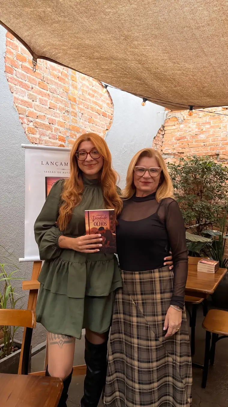 Esther Faria ao lado de uma leitora no dia do lançamento