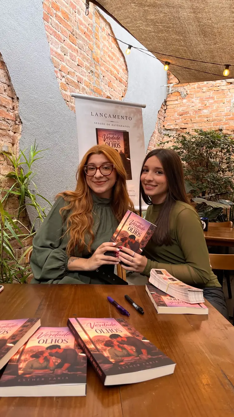 Esther Faria com uma leitora segurando o exemplar autografado