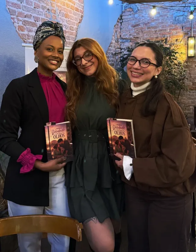 Esther Faria com leitoras segurando o livro no lançamento